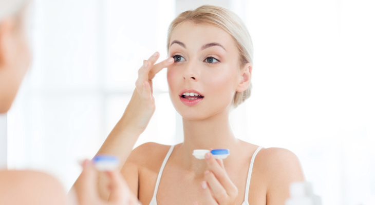 Blonde girl puts in her contacts.